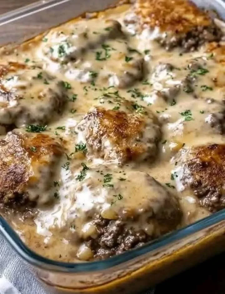 Delicious Amish-style hamburger steak bake served with gravy and sides.