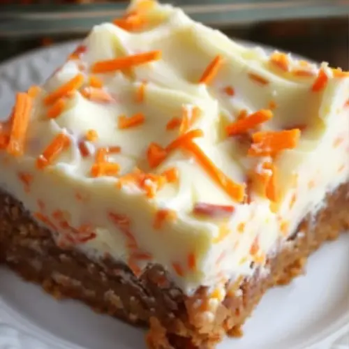 Cream cheese frosted carrot cake bars on a wooden table