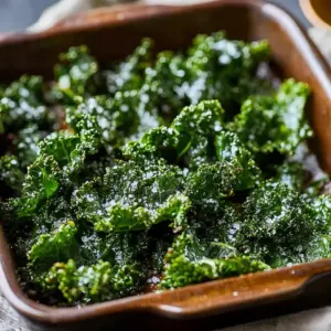 A bowl of crispy garlic parmesan kale chips on a wooden table