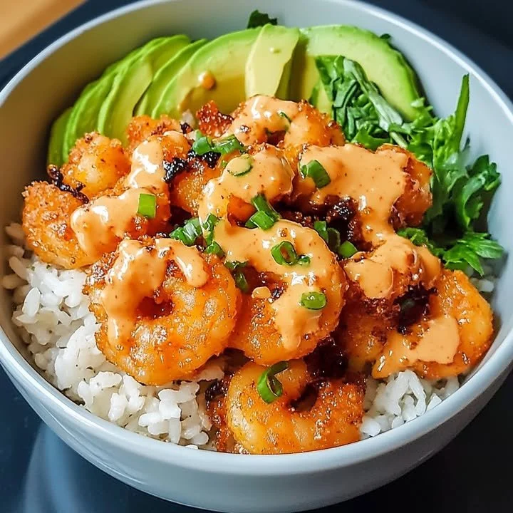 Delicious crispy shrimp bowl garnished with spicy sauce and fresh vegetables.