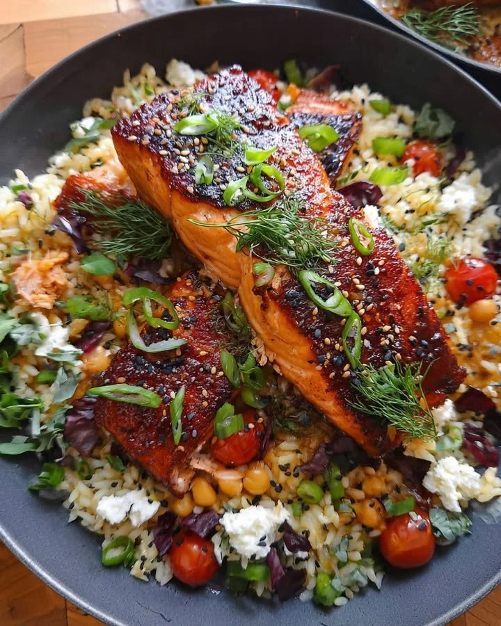 Grilled salmon rice bowl with fresh vegetables and herbs
