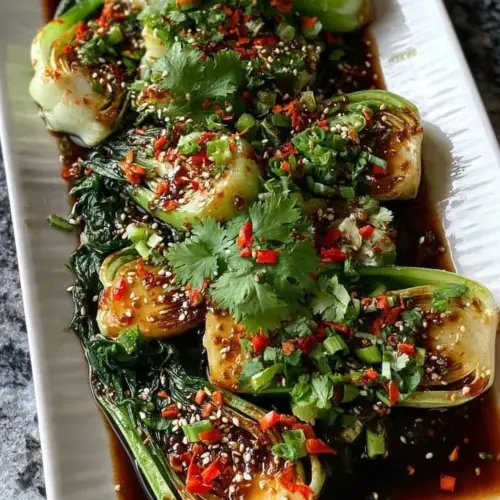 Plate of roasted bok choy with sesame ginger sauce, garnished and ready to serve.