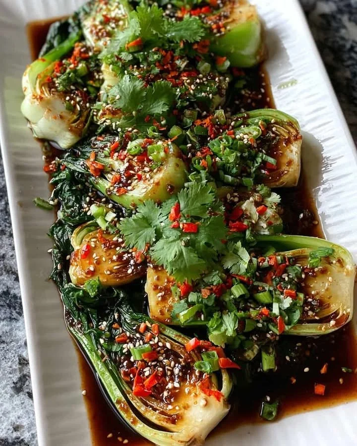 Plate of roasted bok choy with sesame ginger sauce, garnished and ready to serve.